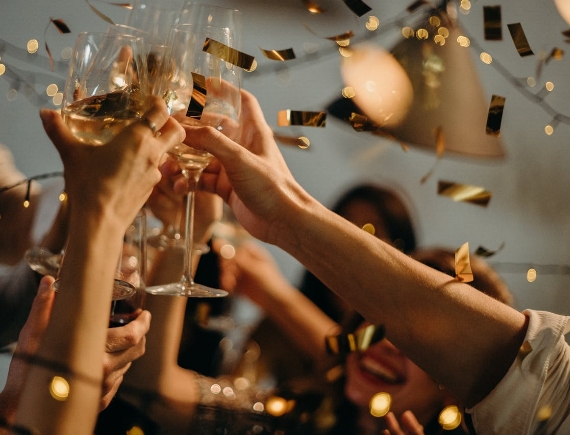 Group of people celebrating with confetti and wine glasses